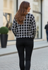 Photo d'une femme portant un pull noir à coupe ample, orné d'un symbole ou motif blanc bien visible  - Les pépites de Christelle
